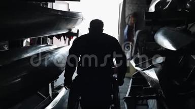 独木舟和皮艇。 一个残疾的残疾人离开仓库，乘坐轮椅从黑暗进入光明。